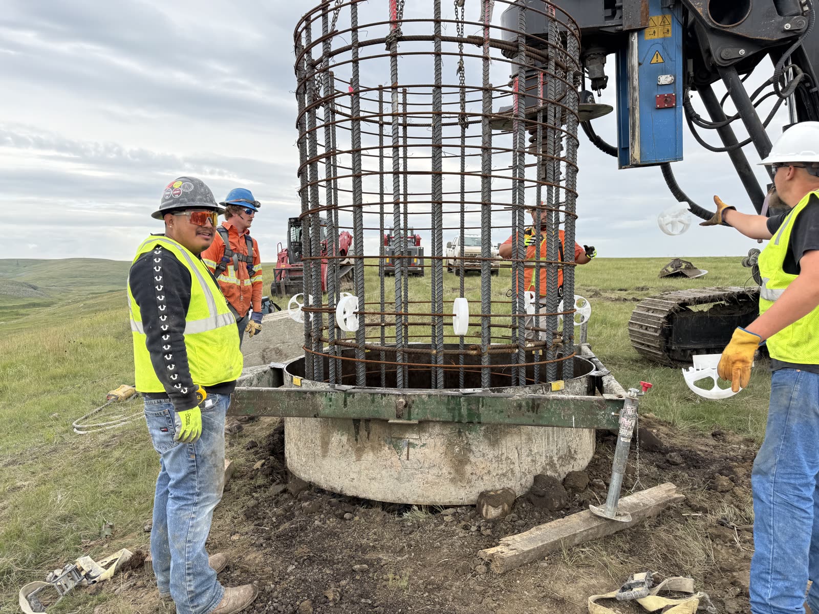 Crew setting a rebar cage on a powerline foundation